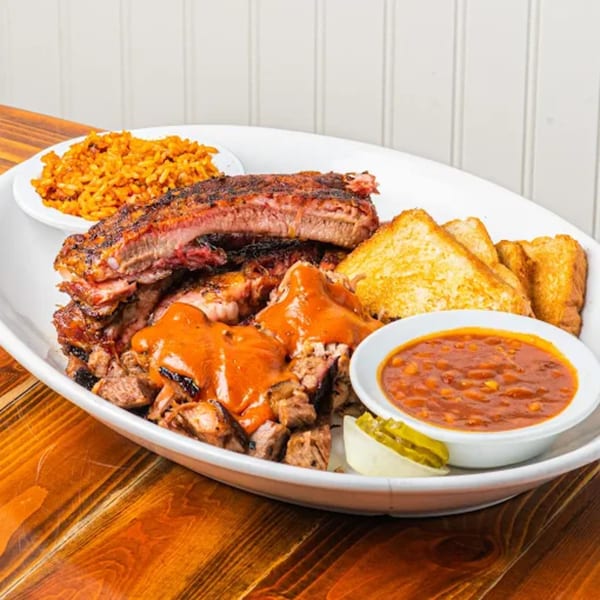A large platter of Barnes Restaurant BBQ ribs, chopped brisket with sauce, baked beans, rice, and toast.