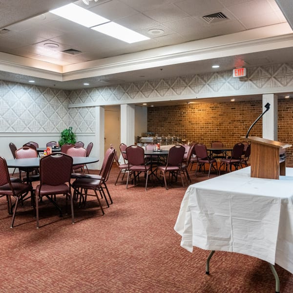 Empty banquet room at Barnes Restaurant with tables, chairs, a buffet, and a podium.