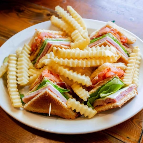 Club sandwiches with ham, cheese, lettuce, and tomato, served with crinkle-cut fries.